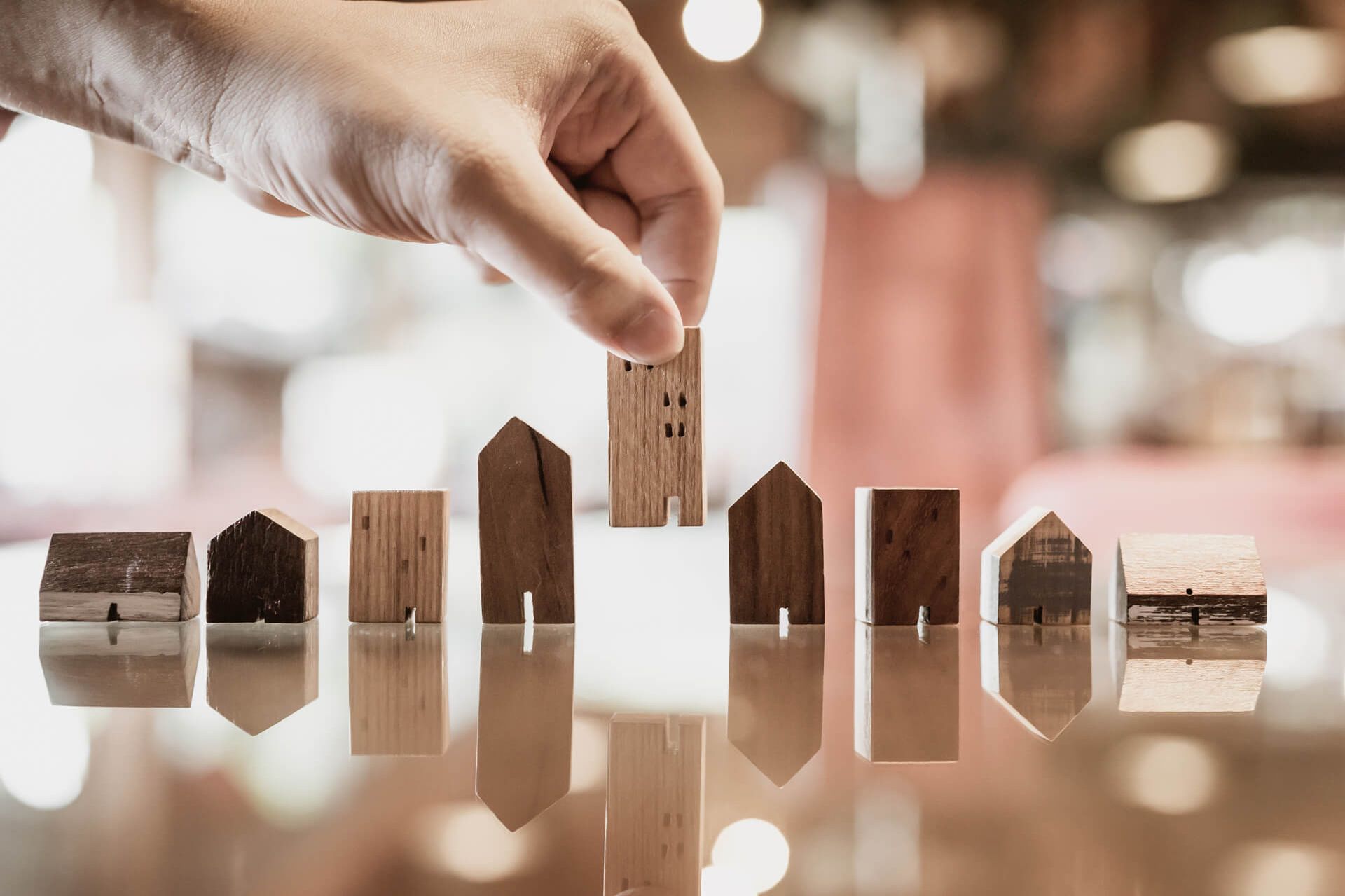 Eine Person hält ein Holzhausmodell auf einem Tisch